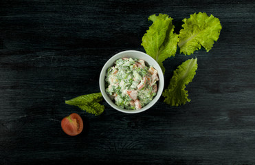 Salad with vegetables. View from above. Fresh salad in a plate on a dark background. Garlic,...
