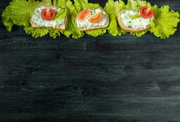 Sandwiches with vegetables. Fresh sandwiches with vegetables on a dark board on a textured background. View from above. Copy space