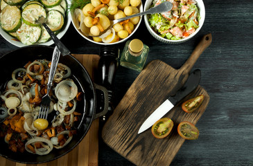 Vegetables on the background. Fried zucchini sauce in a plate. Young boiled potatoes with dill in a bowl. Fried chanterelle mushrooms with golden onions in a frying pan. copy space