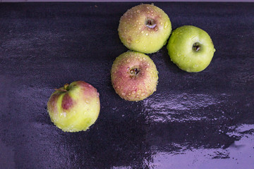 Wet apples on the black background. Drops of water. Green and red fruits.