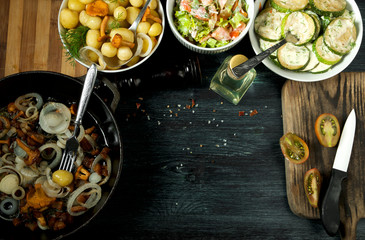 Vegetables on the background. Fried zucchini sauce in a plate. Young boiled potatoes with dill in a bowl. Fried chanterelle mushrooms with golden onions in a frying pan. copy space