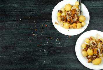 Vegetables on the background. Young boiled potatoes with dill in a bowl with fried chanterelle mushrooms with golden onions on a dark background. copy space.