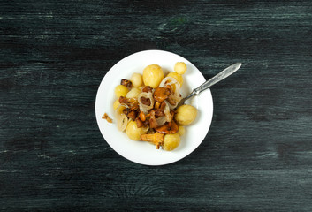 Vegetables on the background. Young boiled potatoes with dill in a bowl with fried chanterelle mushrooms with golden onions on a dark background. copy space.