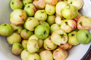 Green and red apples in the white enamelled white bowl.