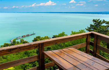 Panoramic view of Lake Balaton and the harbor from Tihany with a wooden table and railing in the foreground in Hungary