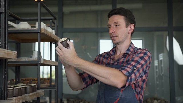 Focused man looking to the handmade cap in the pottery.