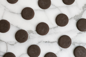 Group of thin mints cookies on white marble background, chocolate mint thin round cookies, top view