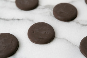 Fototapeta premium Group of thin mints cookies on white marble background, chocolate mint thin round cookies, top view