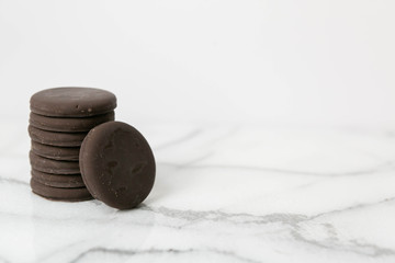 Stack of thin mints cookies on white marble background, chocolate mint thin round cookies