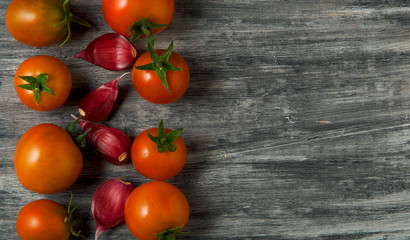 Tomatoes on the background. Tomatoes, garlic on a wooden surface. View from above. Fresh vegetables. copy space.