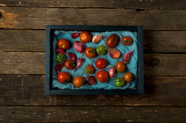 Tomatoes on the background. Tomatoes, garlic on a wooden surface. View from above. Fresh vegetables. copy space.