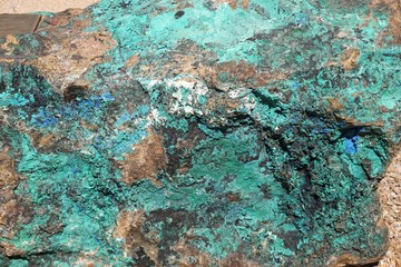 Closeup macro view of natural rock surface with brown, green and blue mineral inclusions