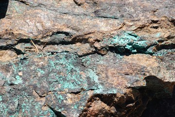 Rough stone boulder with natural green oxidized copper inclusions abstract horizontal background texture