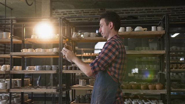 Cute middle age man looking to the handmade cap in the pottery.