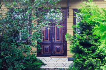 Old Fashioned village wooden house door, house entrance hidden behind trees.