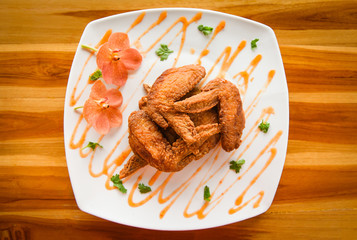Fried chicken wings served on plate with sauce top view - plate of crispy chicken wings on wooden table