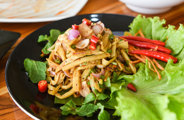 Bamboo shoot dry soup shredded cooked with herbs and spices ingredients and fresh lettuce vegetable - Thai bamboo shoot spicy salad served on plate on the wooden table