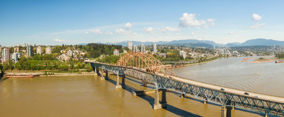 Aerial panoramic view of Pattullo Bridge going over the Fraser River during a sunny day. Taken in Surrey, Greater Vancouver, British Columbia, Canada.
