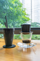 Vietnamese iced fin coffee next to window with cityscape background
