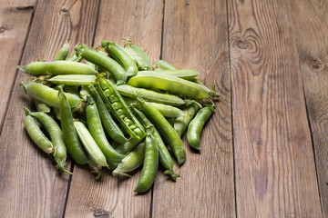 Young fresh green peas in a pod on a wooden table.