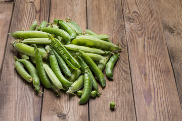 Young fresh green peas in a pod on a wooden table.