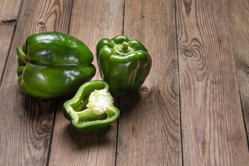 Set of fresh young green peppers on a natural wooden table.