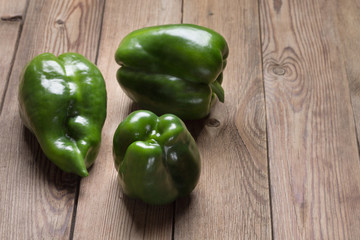 Set of fresh young green peppers on a natural wooden table.