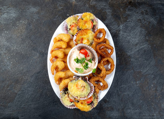 PERUVIAN FOOD. Piqueo caliente. Hot seafood platter fried shrimps, squid rings and baked scallops with sauce