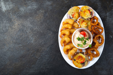 PERUVIAN FOOD. Piqueo caliente. Hot seafood platter fried shrimps, squid rings and baked scallops with sauce 