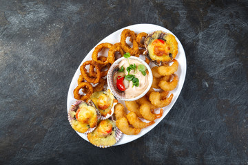 PERUVIAN FOOD. Piqueo caliente. Hot seafood platter fried shrimps, squid rings and baked scallops with sauce 