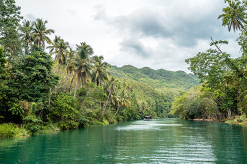 Bohol Loboc river cruise on Philippines. Palms, cloudy sky, hills