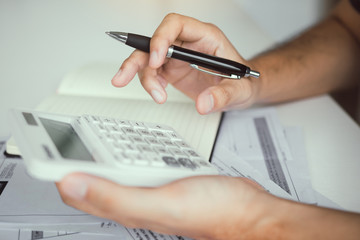 Man use calculators and documents that calculate expenses in the home office.