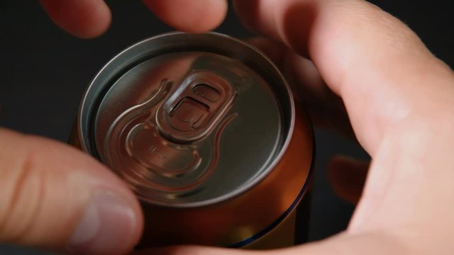 Man hand opening soda or beer can. Close up of can pull tab opening.