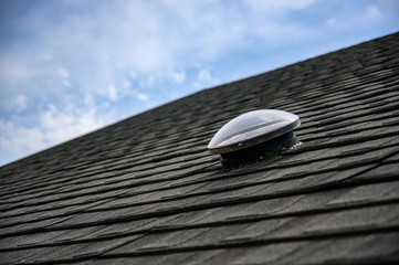 Dome shaped solar tube skylight on asphalt shingle roof 