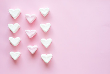 Heart-shaped marshmallow on a pink background laid out in order.