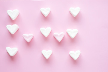 Fototapeta premium Marshmallow in the shape of a heart on a pink background laid out in a pattern. There is a place for text. Flat lay.