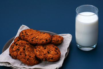 Chocolate breakfast cookies with a glass of milk on a turquoise table