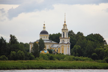 Fototapeta na wymiar Russia, Tver region, Kimry, White town - St. Nicholas Church on the banks of the Volga river, view from water on cloudy summer day