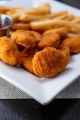 A closeup of a plate featuring chicken nuggets and french fries