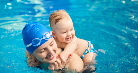 Child having fun in water with mom. Little wet boy smiling holding on his mother's back and happy...