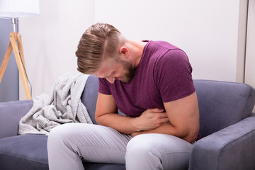 Man Having Stomach Pain Sitting On Sofa
