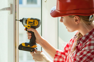 Woman using drill on window