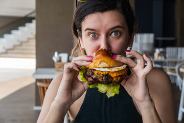 Young girl eats burger, american unhealthy calories meal. Unhealthy eating concept