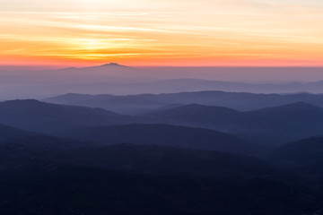 Beautifully colored sky at sunset, with mountains layers and mist between them