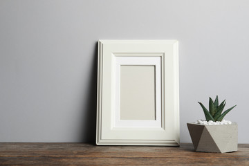 Blank frame and beautiful succulent plant on table against light background, space for design. Home decor