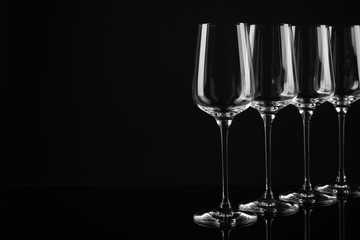 Set of empty wine glasses on black background. Space for text