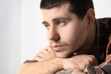 Obraz premium Young man with pierced eyebrow on light background