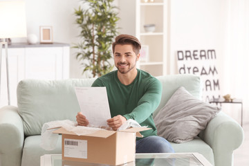Young man unpacking parcel at home