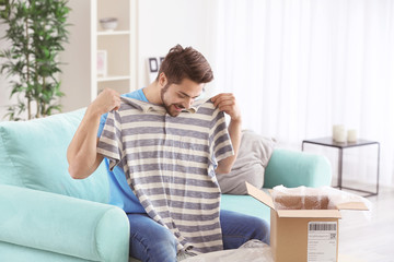Young man unpacking parcel at home