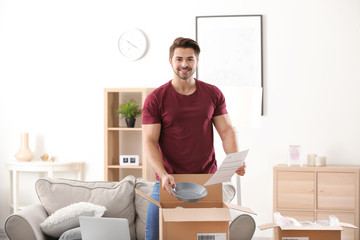 Young man unpacking parcel at home